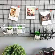 Grade de parede com fotos penduradas e cestos com plantas