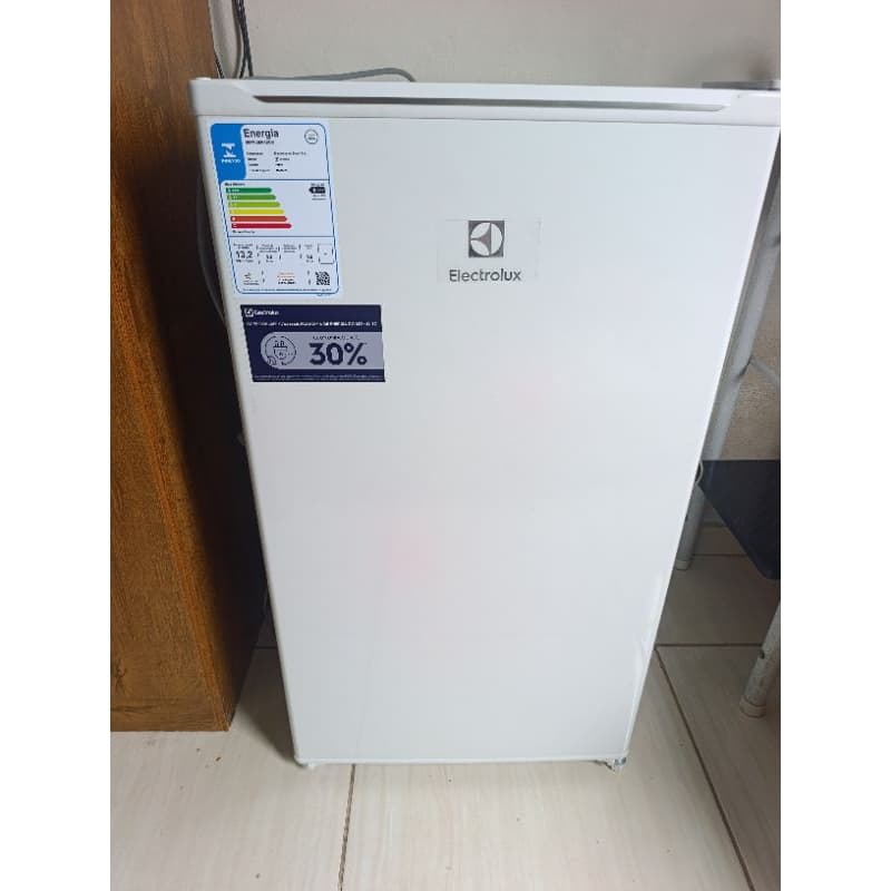 Frigobar branco Electrolux em pé no canto de uma sala com piso de ladrilhos