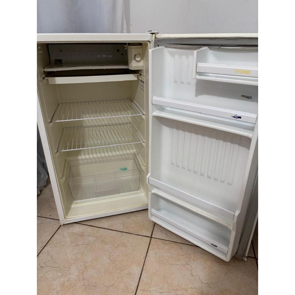 Frigobar compacto branco aberto com interior vazio e prateleiras transparentes