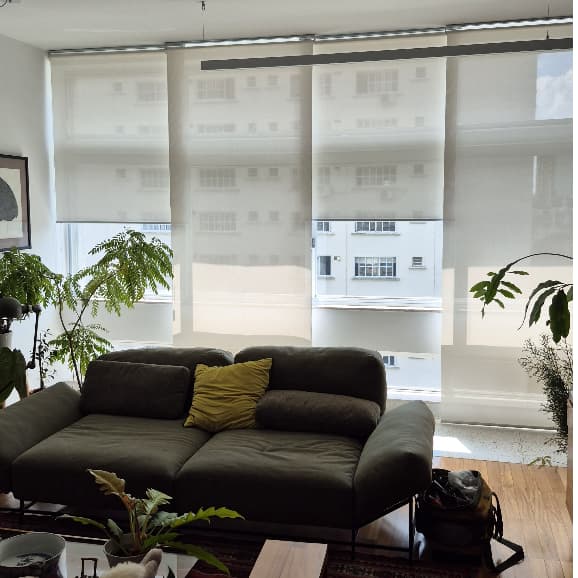 Persianas rolo brancas com proteção UV e visibilidade externa em uma janela de apartamento