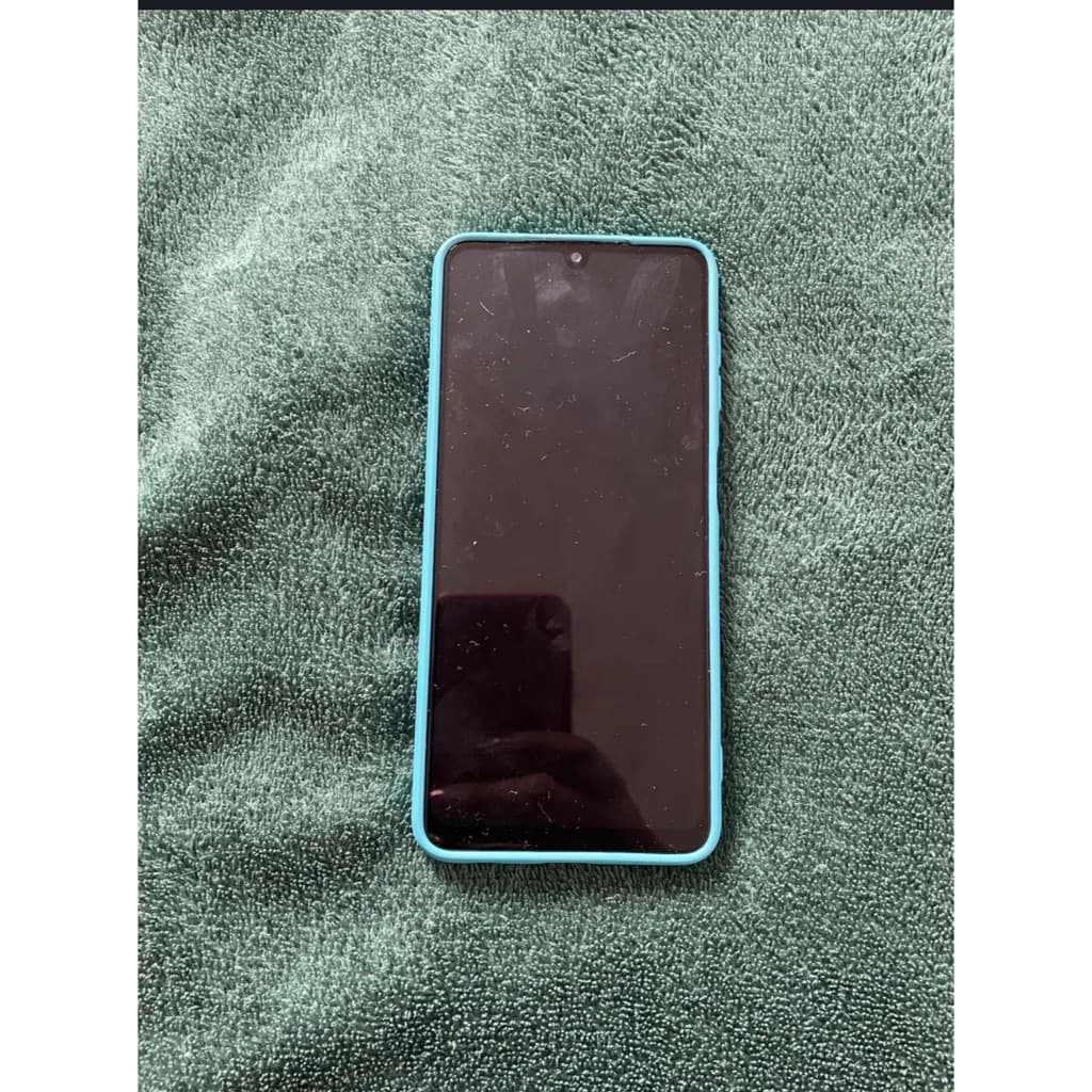 Smartphone Samsung Galaxy A22, cor turquesa, em fundo verde, mostrando a tela e borda.