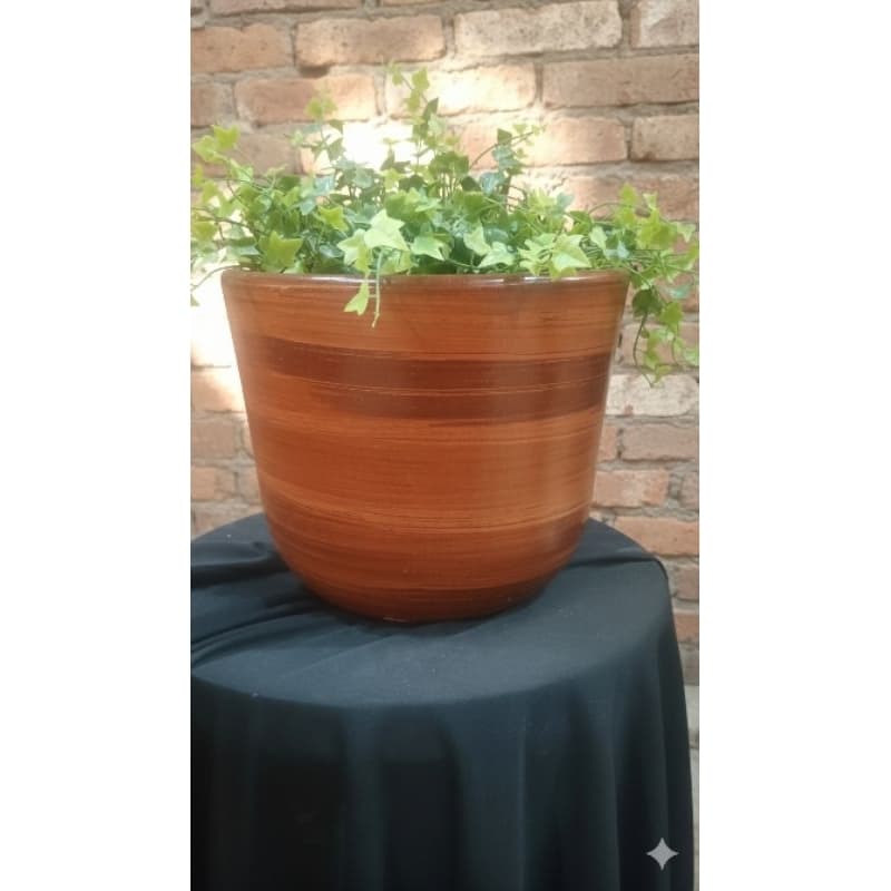 Cachepô de cerâmica terracota grande com planta verde sobre mesa com fundo de tijolos