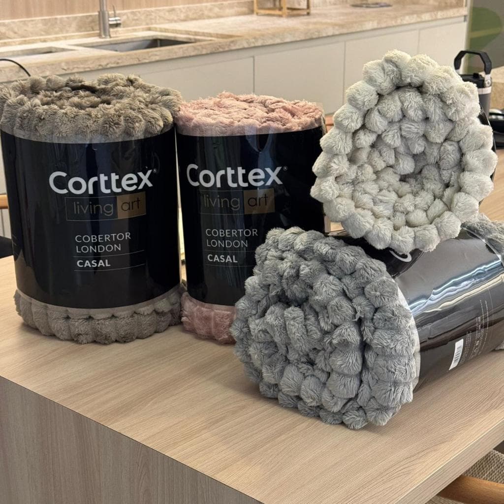 Cobertores canelados Corttex cinza, rosa e branco em uma mesa de madeira