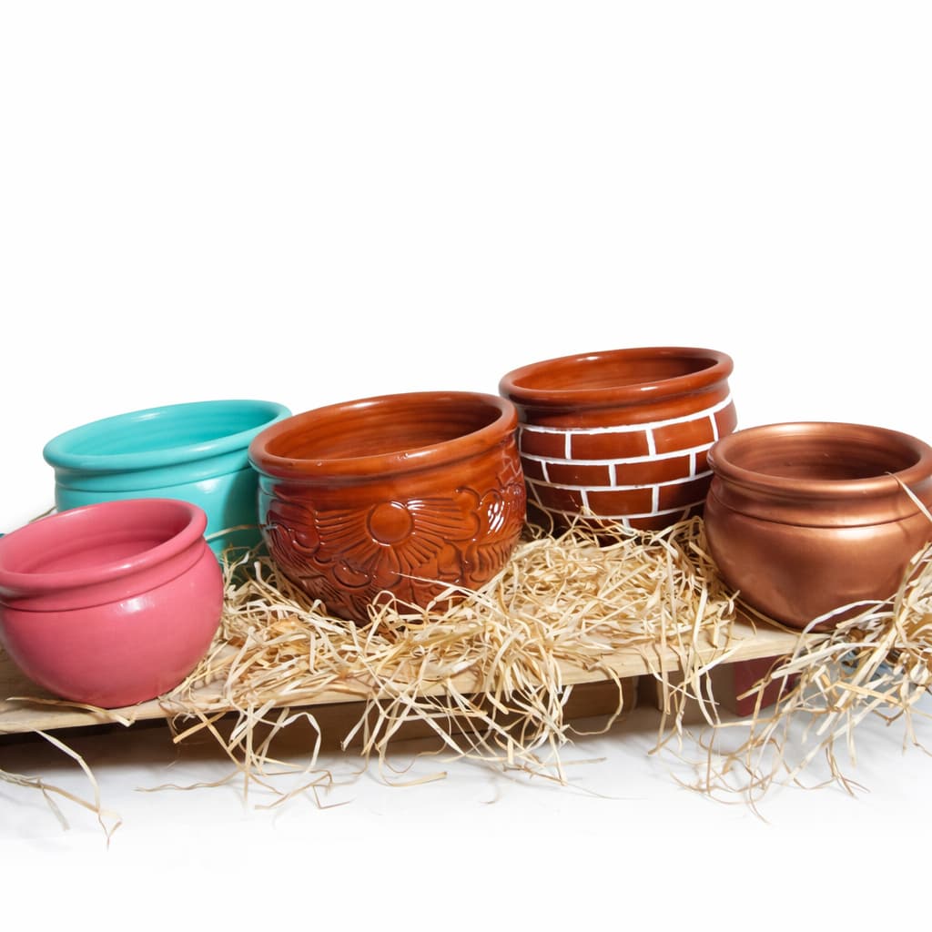 Vasos de barro coloridos em suporte de madeira com palha