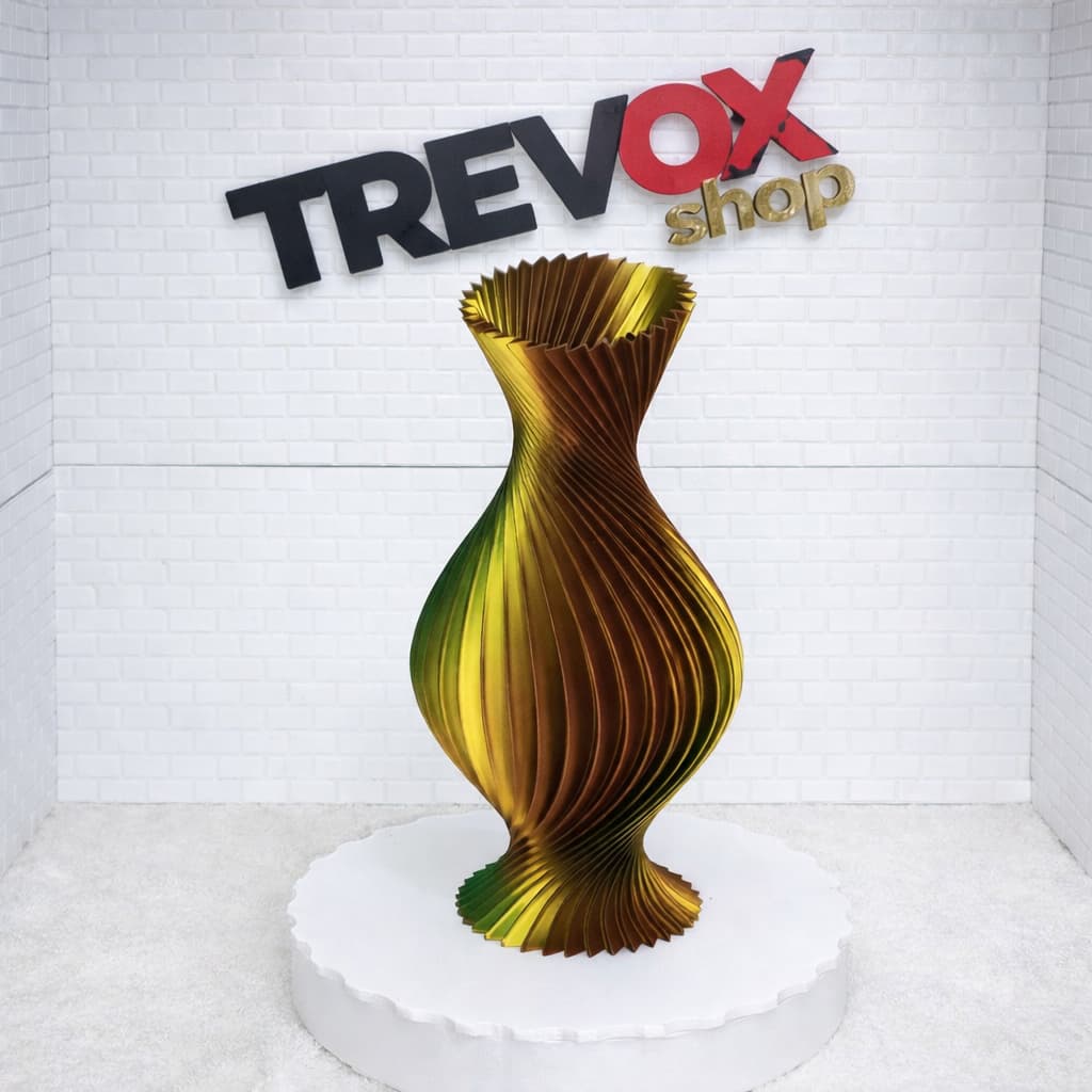 Vaso decorativo espiral dourado e verde em pedestal branco, ideal para decoração de sala, mesa ou escritório.