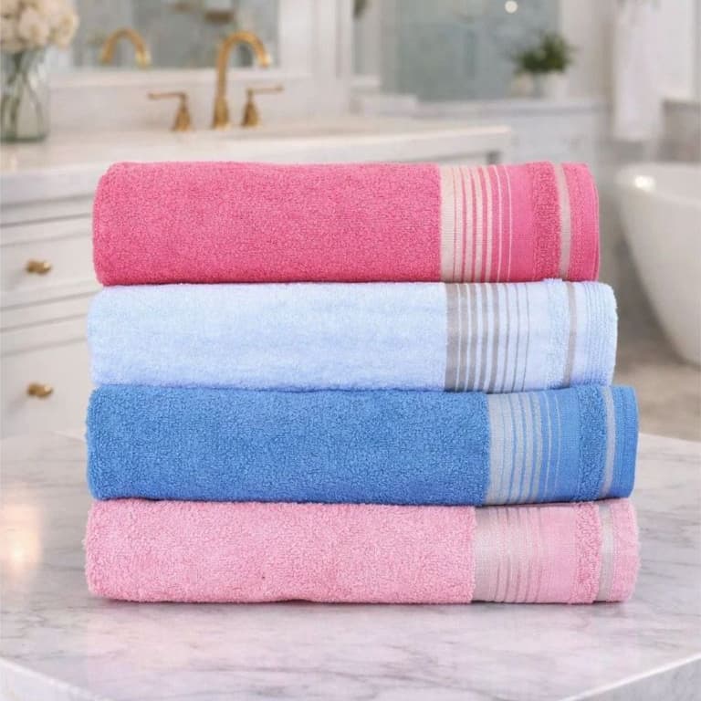 Toalhas de banho de algodão 100% em pilha, cores rosa, azul claro e azul escuro, com listras horizontais, sobre uma superfície de mármore.