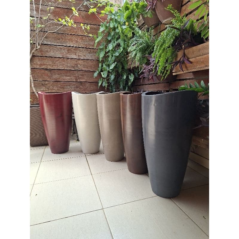 Vasos para plantas Vasart altos e grandes em cores vermelho, bege, marrom e preto, dispostos em fileira.