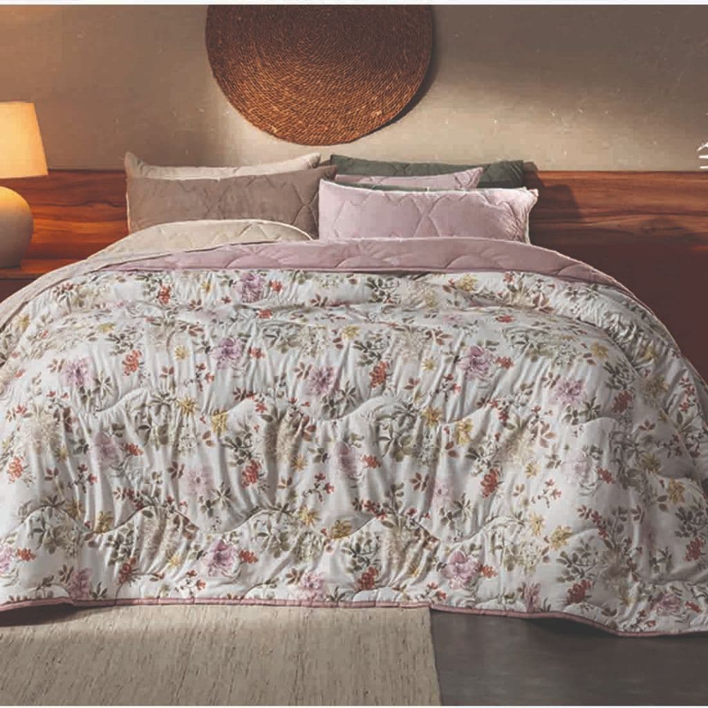 Edredom floral branco e rosa com padrão de flores em uma cama decorada