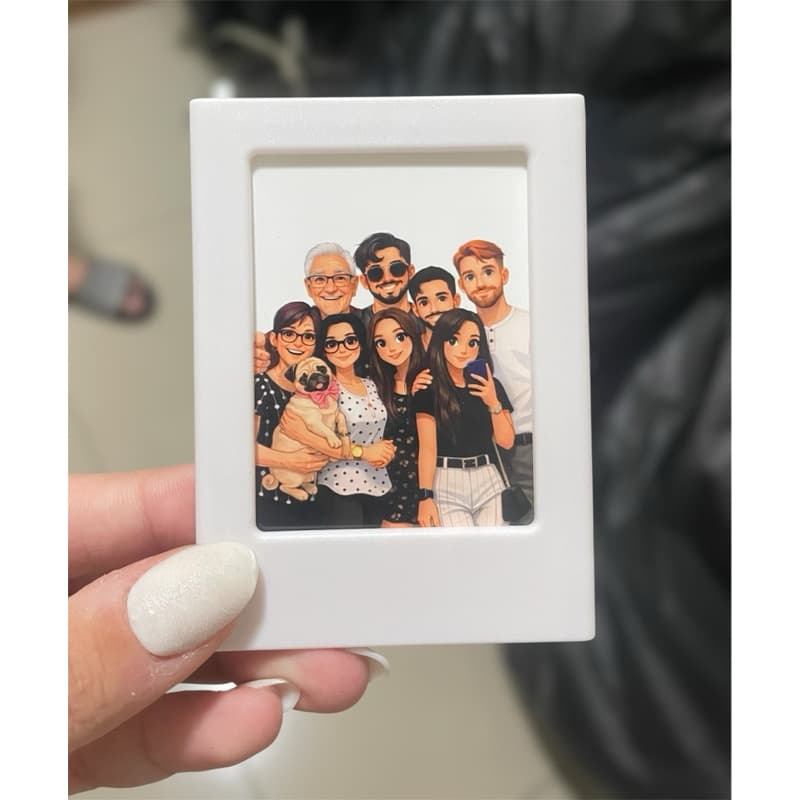 Porta-retrato magnético branco com foto de família e cachorro, segurado por uma mão com unhas pintadas.