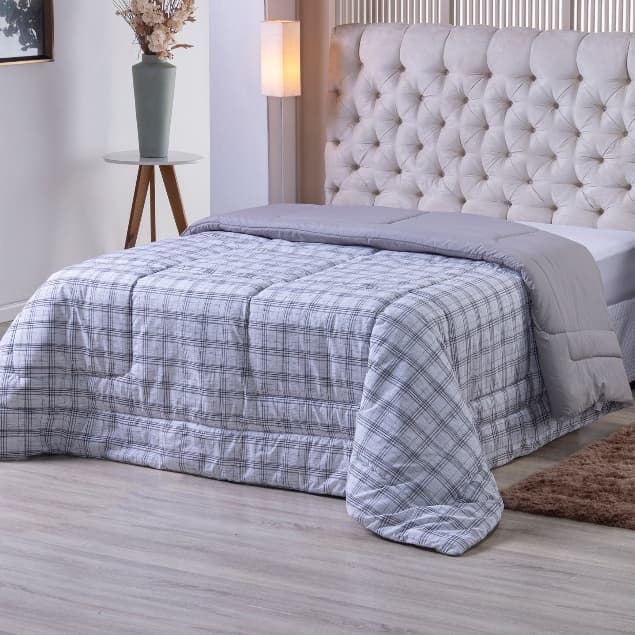 Edredom duplo face solteiro estampado cinza e branco sobre cama com cabeceira estofada
