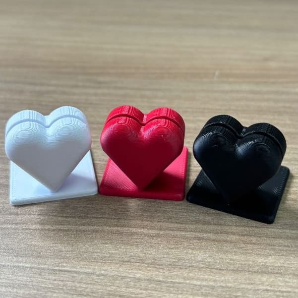 Porta-retratos em forma de coração 3D, branco, vermelho e preto, sobre uma superfície de madeira