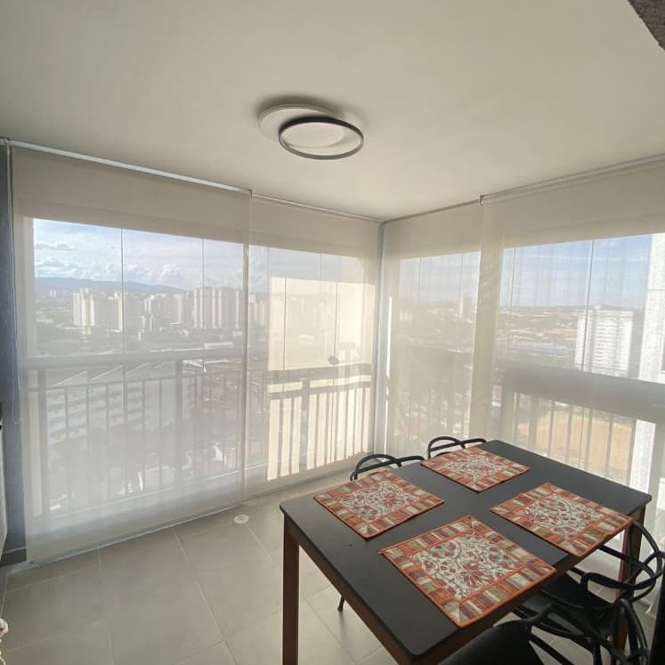 Varanda com mesa de jantar e persianas rolo de tela solar transparente