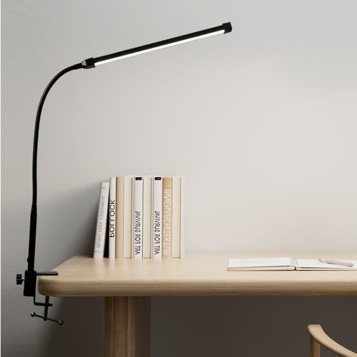 Luminária de mesa LED com clipe de mesa, iluminando uma mesa de madeira com livros ao fundo