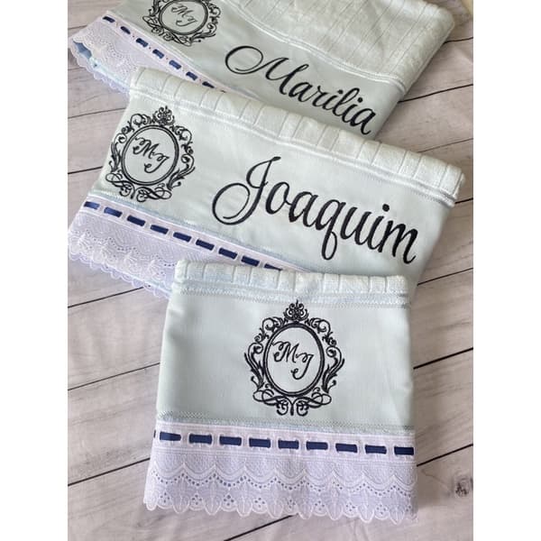 Três toalhas de banho bordadas personalizadas com nomes em preto sobre fundo branco e azul marinho