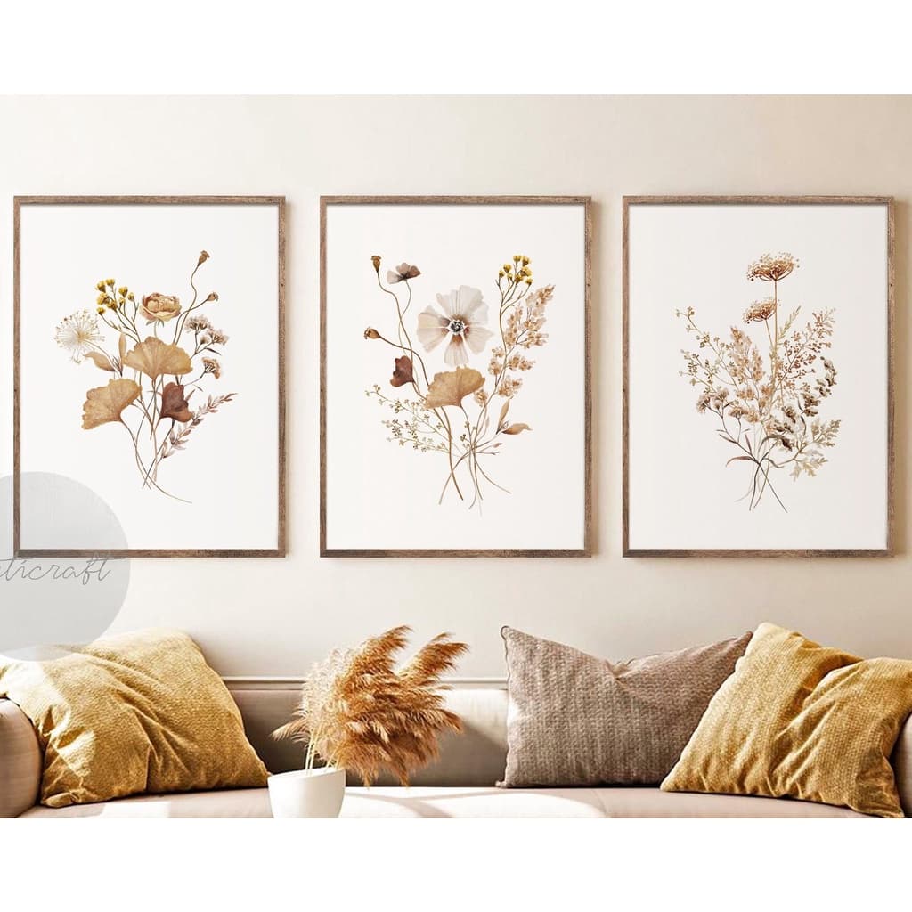 Quadros decorativos com flores botânicas em tons de amarelo e marrom, parede branca, sofá cinza, almofadas amarelas e creme