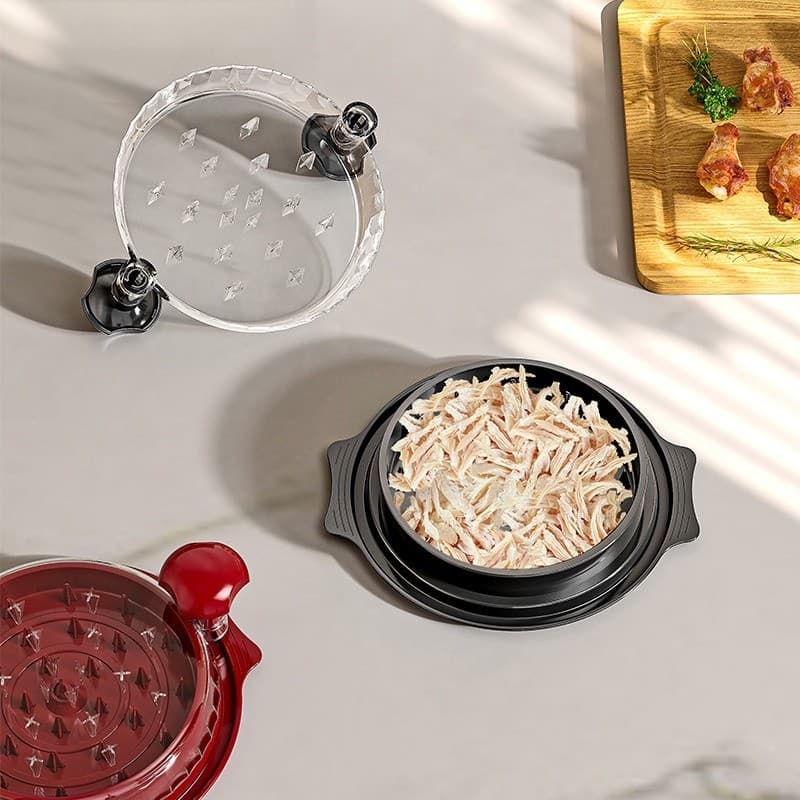 Desfiador manual de alimentos multifuncional com componentes transparentes e pretos, pedaços de carne desfiada em tigela preta.