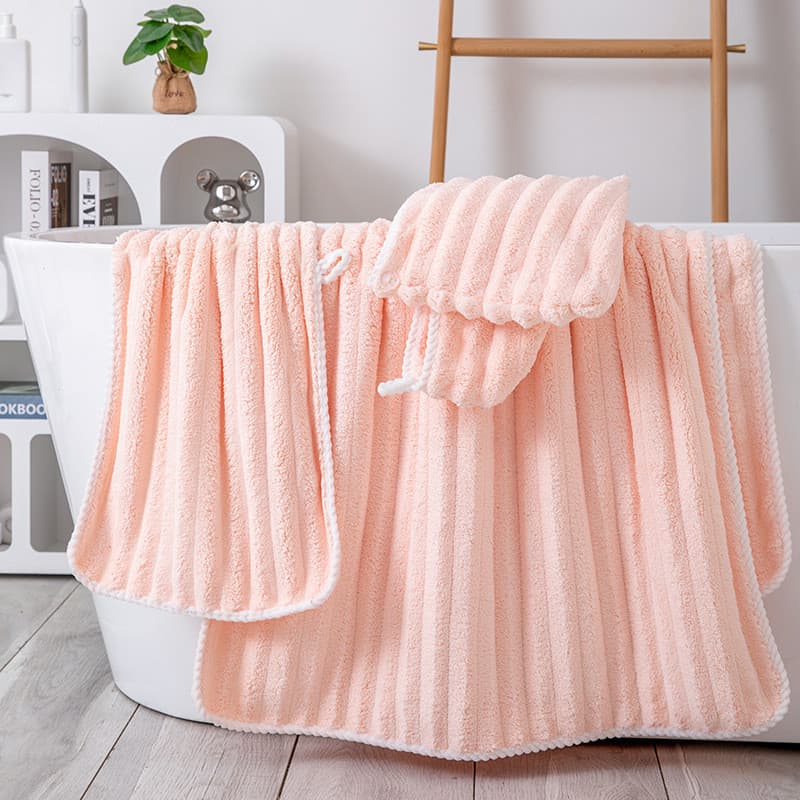 Toalha de banho rosa coral larga e listrada em coral fleece, pendurada sobre banheira