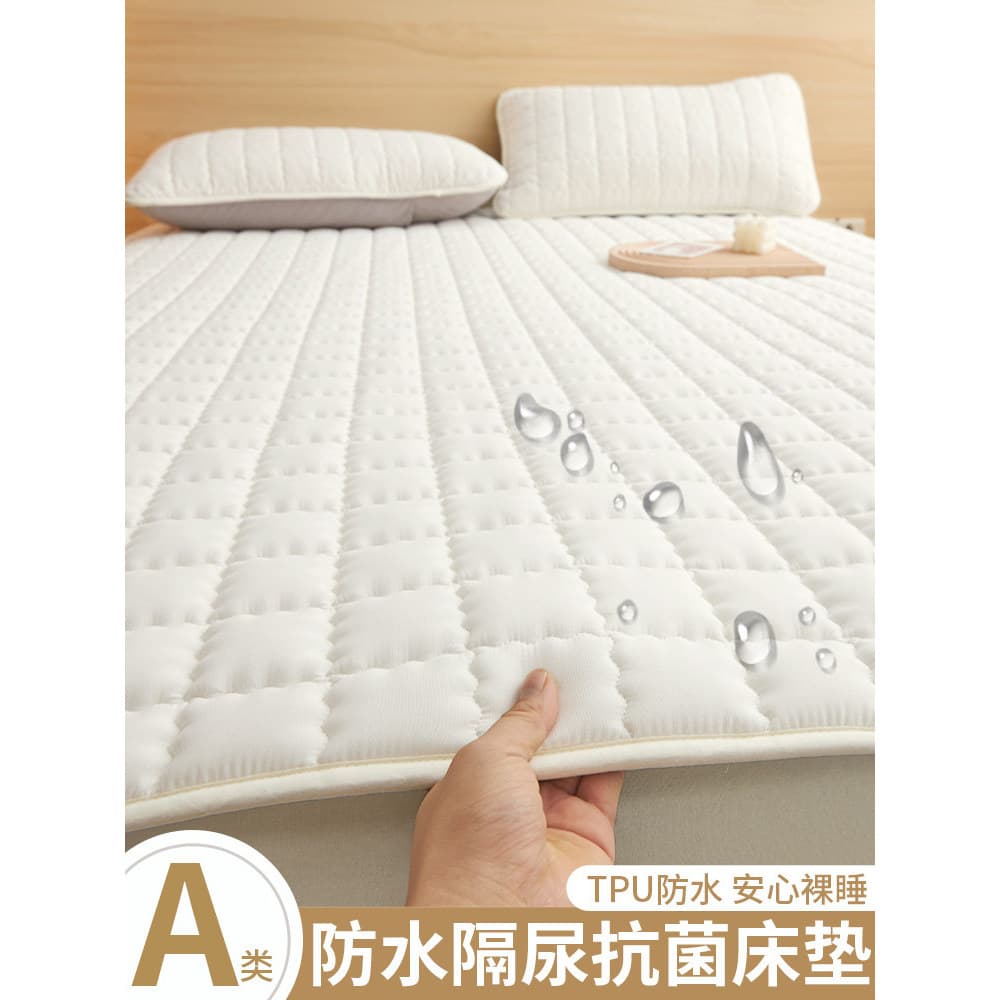 Colchão à prova d'água e de fraldas branco sobre cama, com travesseiro branco.