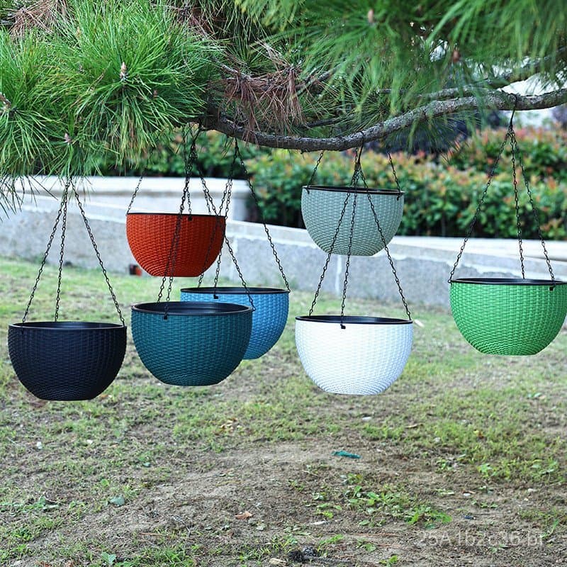 Vasos suspensos Aimei para orquídeas em cores vibrantes, pendurados em uma árvore em um jardim.