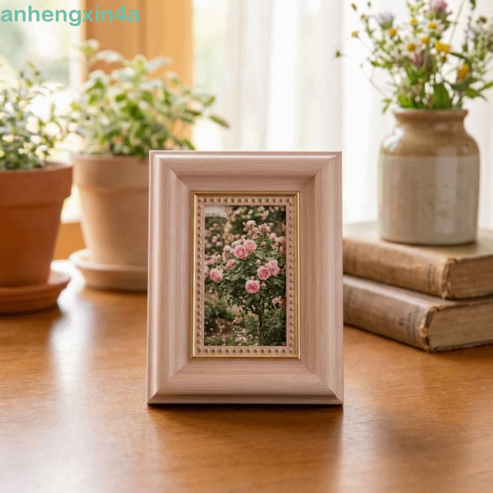 Quadro de porta-retratos de madeira com moldura dourada, imagem de rosas, mesa de madeira, vasos com plantas e livros antigos