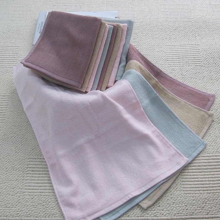 Toalhas de fibra de bambu em cores pastel empilhadas em fundo cinza