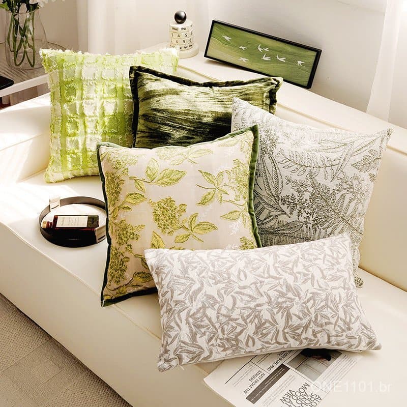 Almofadas decorativas verde e branca em sofá branco, estilo nórdico, para sala de estar.
