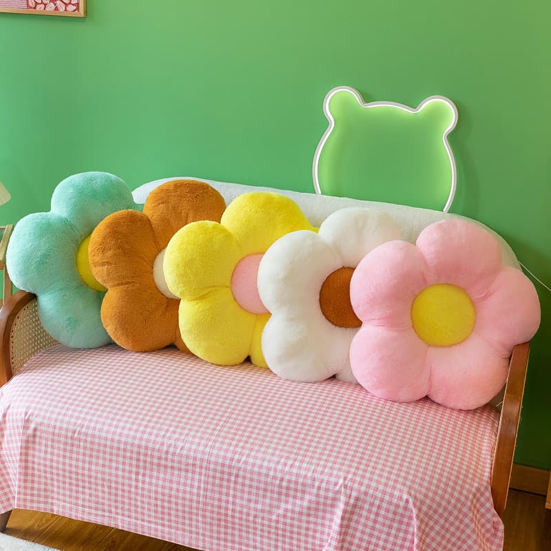 Almofadas florais multicoloridas em forma de flor em um sofá com fundo verde