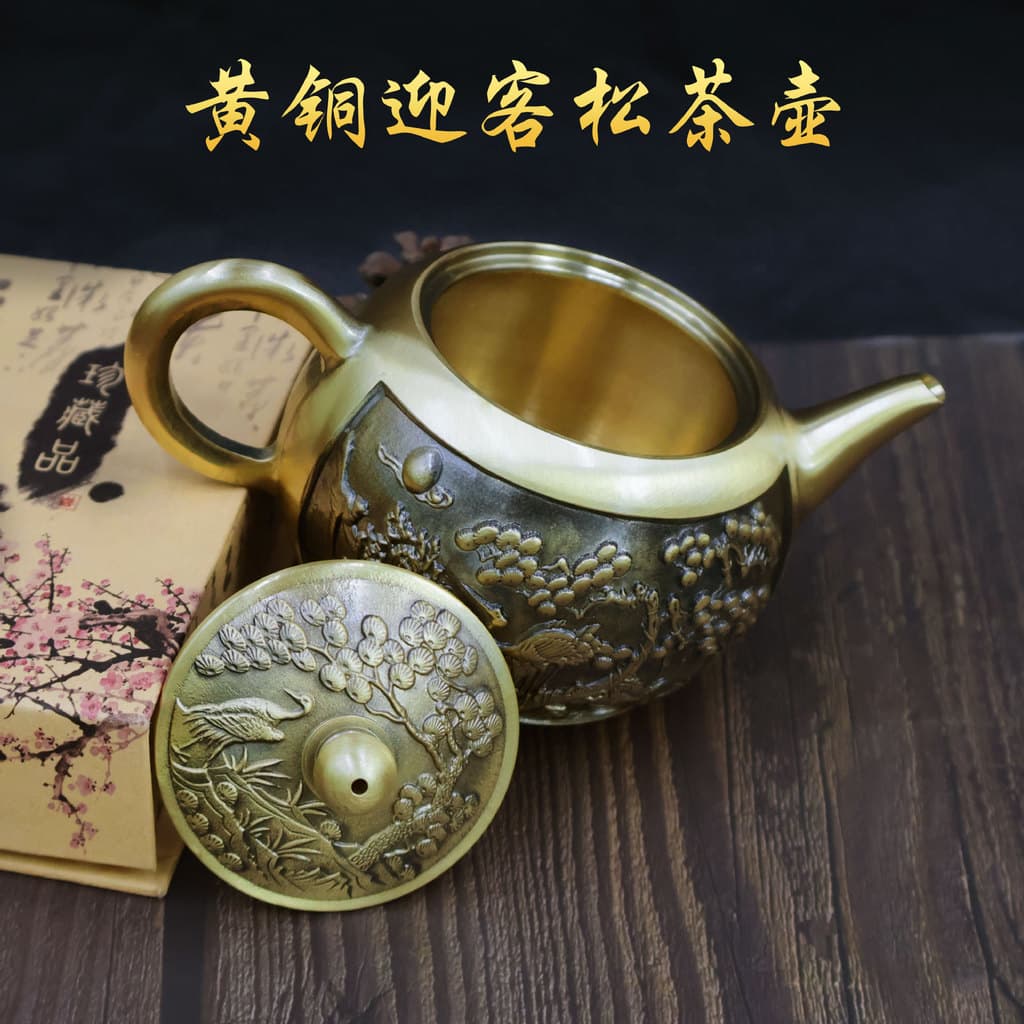 Bule de bronze com detalhes florais e de pássaros em relevo, sobre fundo de madeira escura, texto em chinês amarelo.