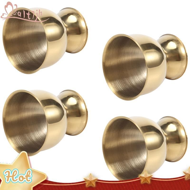 Quatro copos de ovo de aço inoxidável dourados em fundo branco com decoração vermelha e estrelas