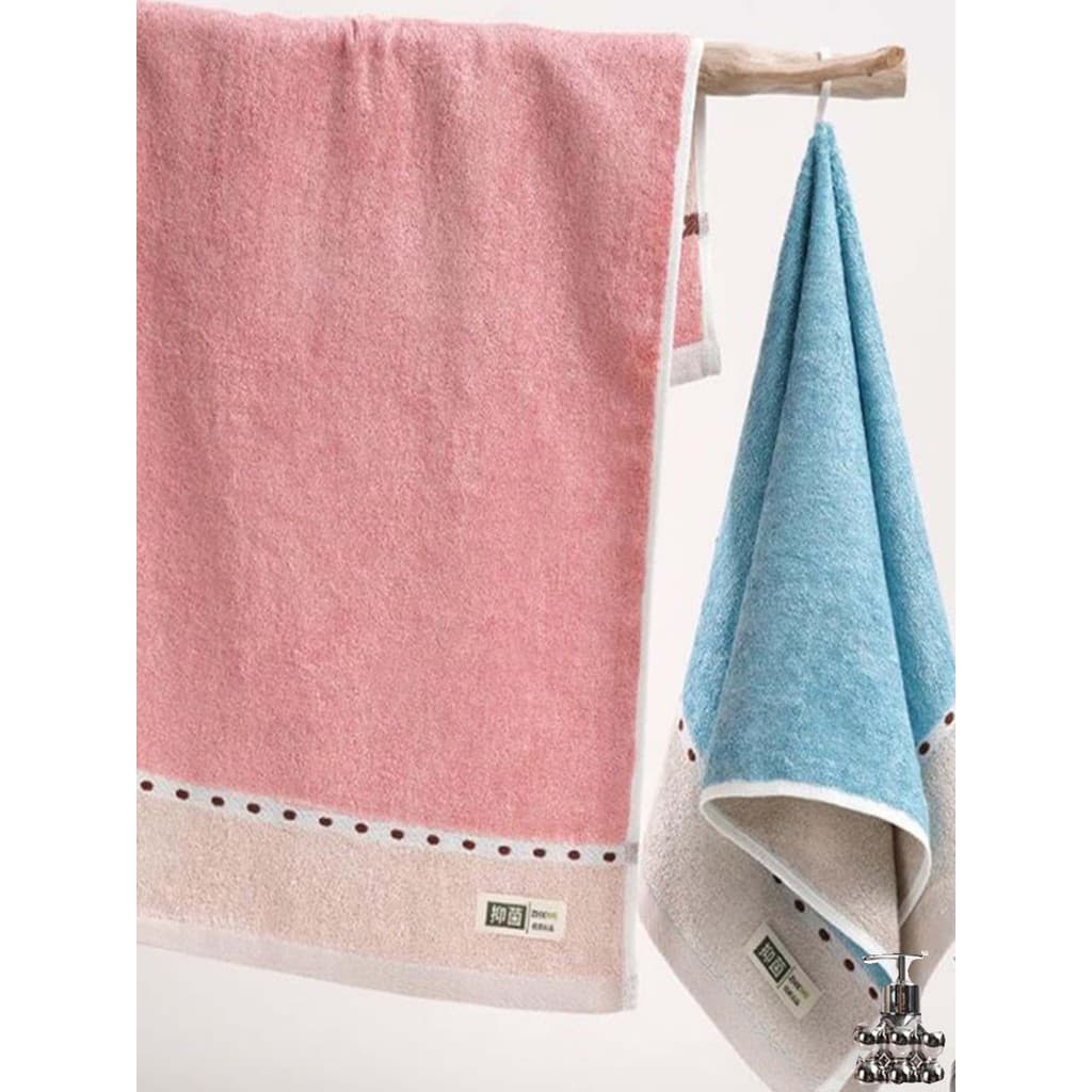 Toalhas de banho Oria de fibra de bambu em rosa e azul com bordas bege e pontos pretos.