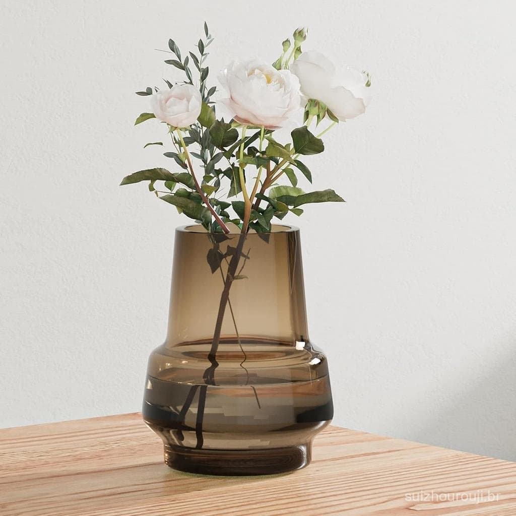 Vaso de vidro marrom com design moderno e boca larga, contendo rosas brancas, em uma mesa de madeira.