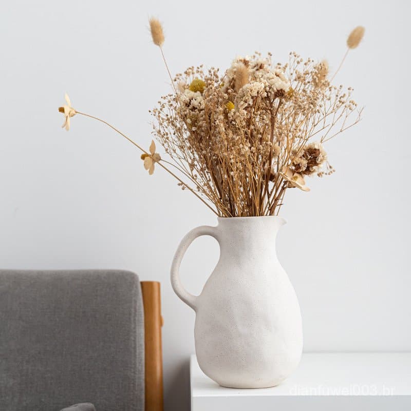 Vaso de cerâmica branco com flores secas em um fundo minimalista