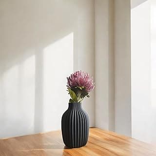 Vaso decorativo canelado preto com flor roxa sobre mesa de madeira