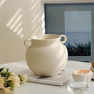 Vaso decorativo em forma de mel, cor creme, com orelhas, sobre mesa com vela e flores