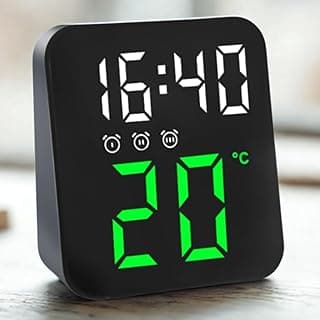 Relógio digital preto com display LED, mostra hora e temperatura, ícones de alarme e ajuste, fundo claro, superfície de madeira.