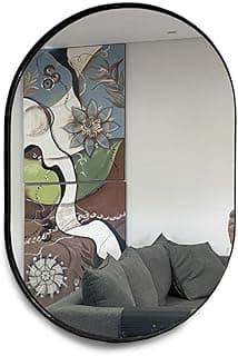 Espelho oval preto 60x40cm com moldura refletindo sala de estar com sofá cinza e pintura artística