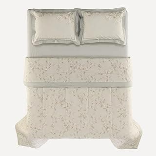 Edredom Karsten Dandara com estampa floral cinza e branco, disposto em plano frontal com dois travesseiros