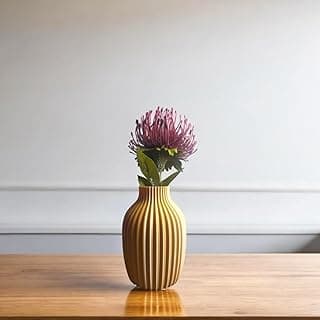 Vaso decorativo canelado caramelo com flor roxa em pé sobre uma mesa de madeira