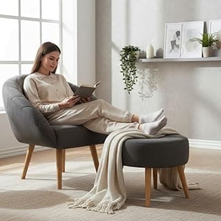 Poltrona cinza com pés de madeira e puff cinza em um ambiente minimalista.
