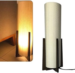 Luminária de solo alta com base em madeira escura e difusor cilíndrico em MDF, acesa emitindo luz suave.