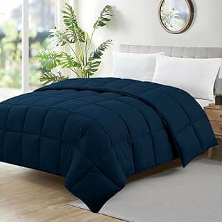 Edredom azul escuro dobrável para cama de solteiro em um quarto com fundo branco e uma planta verde.