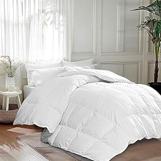 Edredom de penas de ganso branco em cama com lençóis brancos, quarto minimalista com móveis e paredes brancos, iluminação natural.