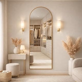 Espelho oval dourado de chão refletindo sala minimalista branca