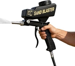 Máquina de jateamento preta em uso, bico de jato de areia, palavra 'SAND BLASTER' em amarelo
