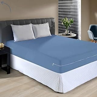 Capa protetora para colchão casal azul em uma cama com cabeceira estofada e travesseiros brancos