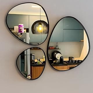 Conjunto de espelhos decorativos orgânicos pretos com formato de folha montados na parede de uma cozinha.