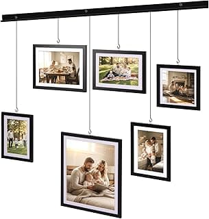 Sete quadros pretos suspensos em uma linha horizontal contra uma parede branca