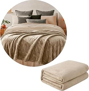Manta de microfibra bege sobre cama com almofadas, textura aveludada, fundo branco