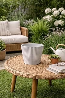 Vaso decorativo branco com padrão de ondas em um centro de mesa de vime, em um jardim com plantas e flores brancas.