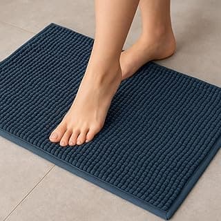 Tapete de banheiro azul escuro de microfibra com textura macarrão bolinha, antiderrapante, com pé descalço apoiado.